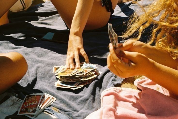Friends playing cards on a picnic blanket in the sunshine